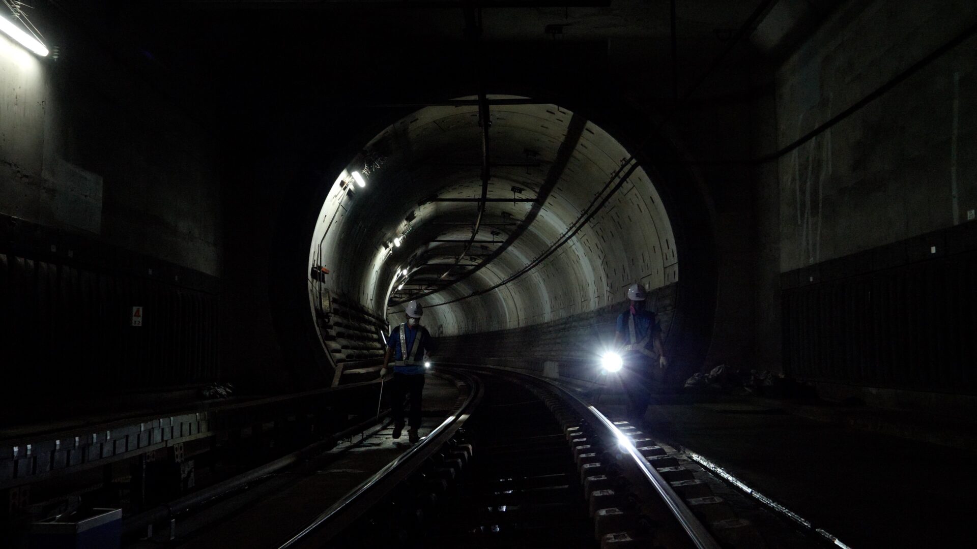 언더그라운드 스틸컷1.어둡고 긴 지하터널 안에 노동자 두 명이 선로를 따라 걷는다. 노동자들은 선로의 양쪽에서 손전등으로 선로를 비추며 그것을 정비한다.