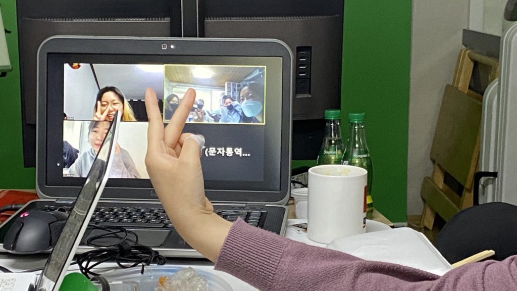 사진. 책상 위 노트북 줌 화면에 자원활동가 요다, 은긍, 문자통역사 화면과 사무실에 모인 활동가들의 화면이 있다.