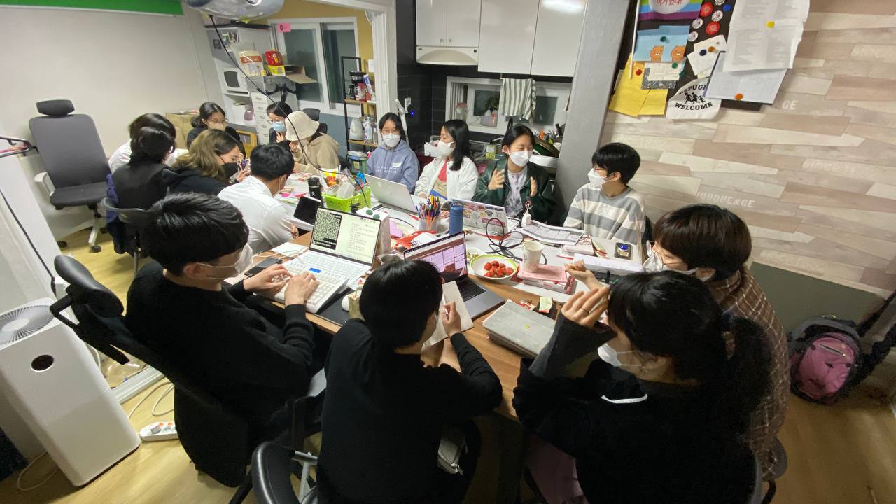 사진. 서울인권영화제 사무실에 길다랗게 책상을 놓고 둘러앉아 회의하는 활동가들.