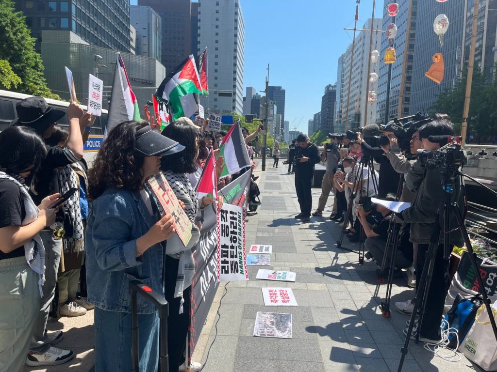 사진2. 한쪽에는 기자회견 참여자들이 피켓과 팔레스타인 국기를 들고 서있다. 맞은편에는 기자들이 카메라, 노트 등을 들고 취재 중이다.
