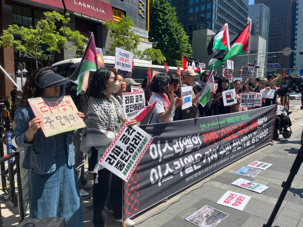 사진1. 기자회견 모습. 참여자들이 붉은 칠을 한 손바닥을 들고 있다. 피켓, 팔레스타인 국기를 든 사람도 여러 사람 있다.