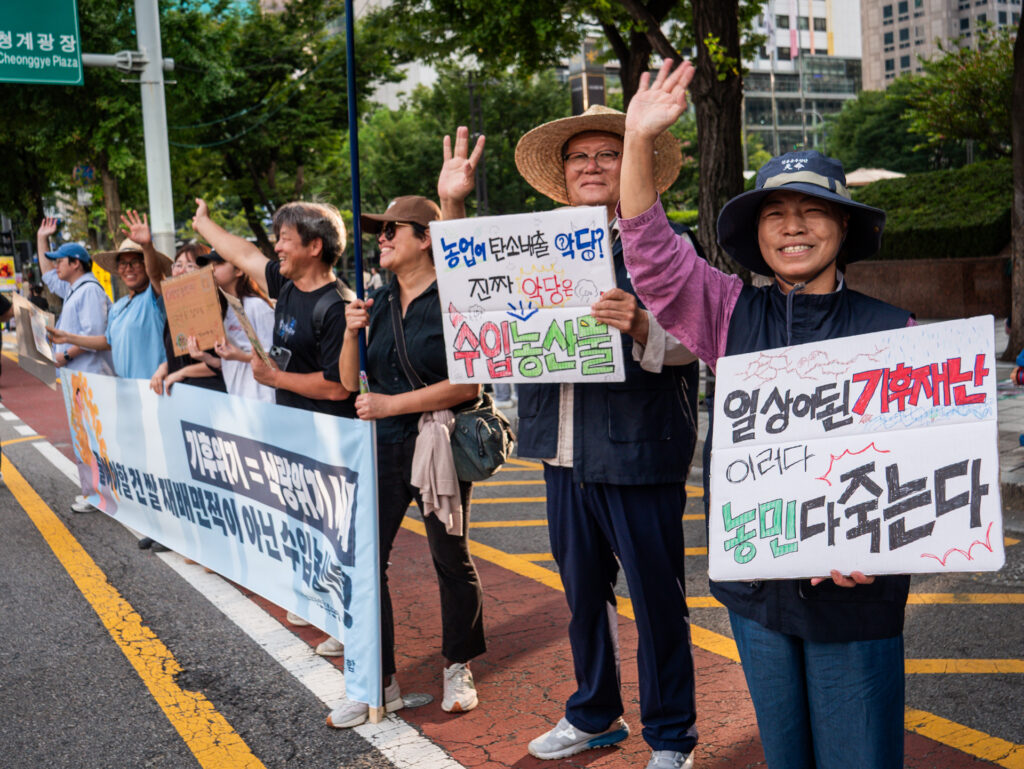 사진6. 2차 농민 거점에서 현수막 피케팅을 하고 있는 전농, 전여농 동지들. 현수막과 피켓에는 ‘기후위기=식량위기 시대, 줄어야 할 건 쌀 지배면적이 아닌 수입농산물!’, ‘농업이 탄소배출 악당? 진짜 악당은 수입농산물’, ‘일상이 된 기후재난 이러다 농민 다 죽는다’고 적혀있다.