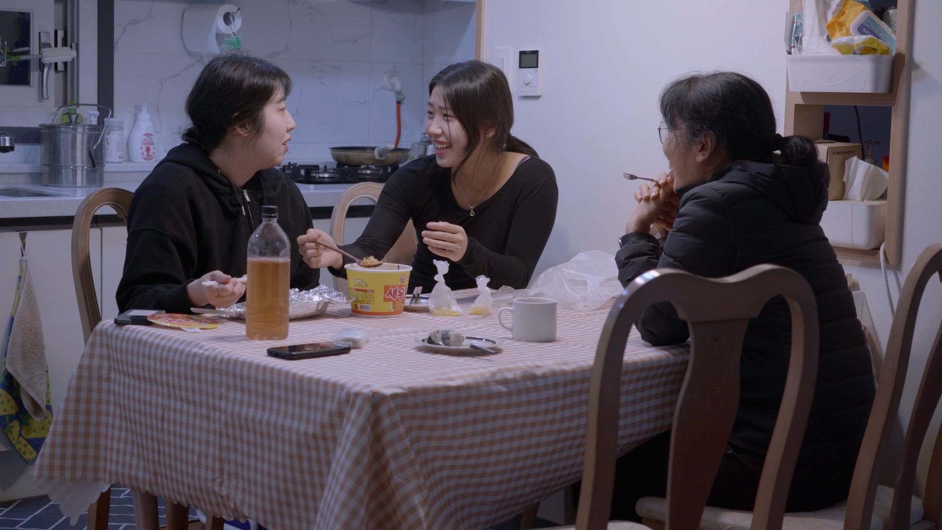 스틸컷7. 세 사람(김동수의 두 딸과 아내)이 식탁에 둘러앉아 웃으며 대화를 나누고 있다. 식탁 위에는 음식이 놓여져있고 나란히 앉은 자매는 숟가락을 들고 있다.