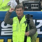 장병철 감독 사진. 연두색 형광 조끼를 입고 카메라를 향해 주먹을 들고 투쟁 포즈.