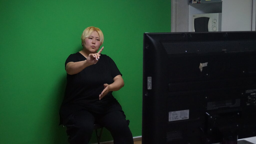사진. 한농퀴 진영 활동가가 모니터를 보며 수어 통역 중이다. 뒤에는 그린스크린.