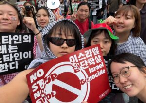 [사진] 서인영 활동가 다 같이~ 효민, 현토, 소하, 안나, 미나상, 고운, 갈채가 카메라를 보고 포즈를 취한다. 쿠피예를 두르고 피켓을 들고 있다. 촬영: 갈채